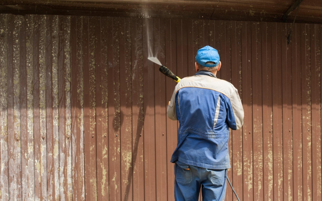 Professional using pressure washer to clean siding