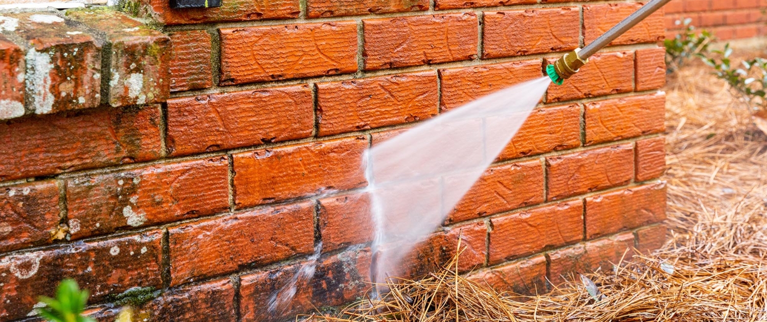 Pressure washer on dirty brick wall