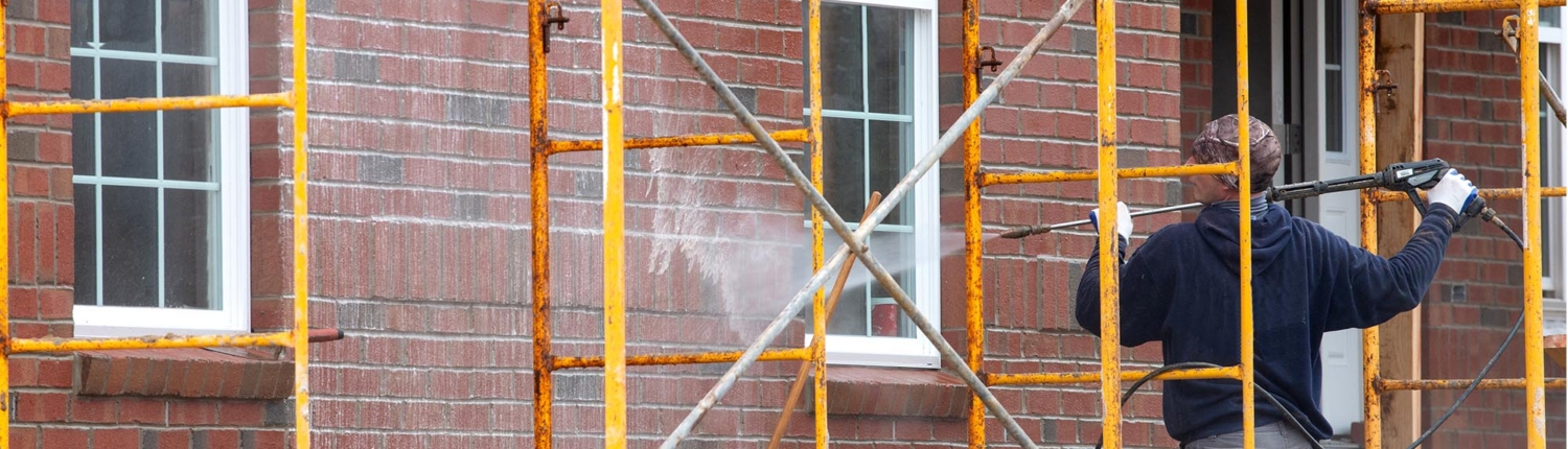 Professional power washing side of brick building
