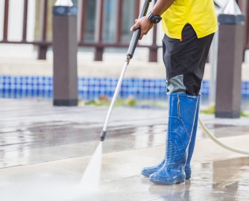 Working person using power washer to clean patio
